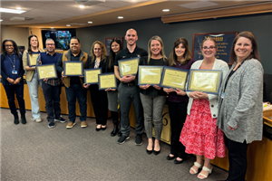  eleven people stand as they are recognized by the board of education